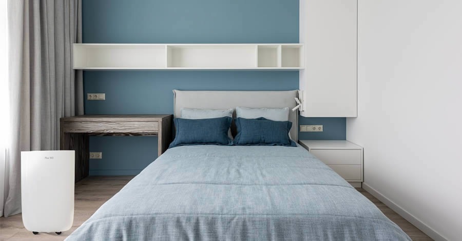 Quarto arrumado com um desumidificador Desidrat New Plus 150 ao lado esquerdo