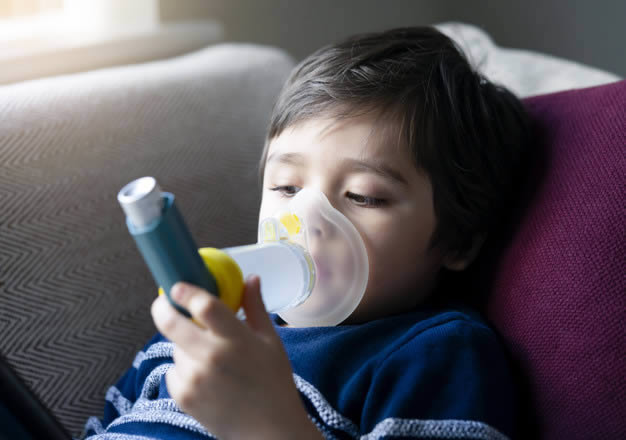 Criança usando uma bombinha de asma em casa