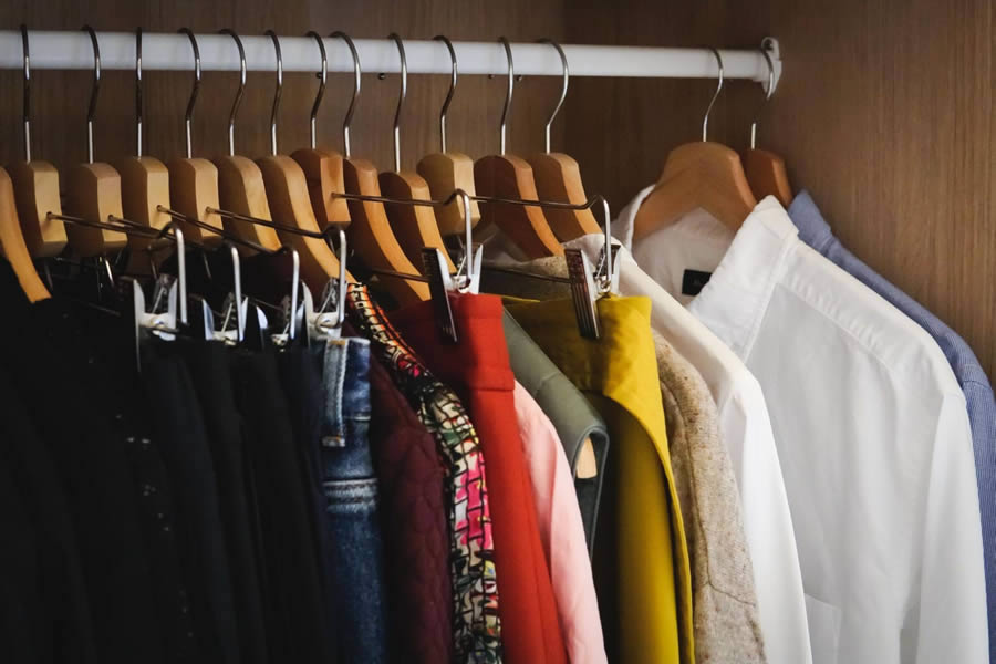 Fotografia de portas do guarda roupas abertas com peças dentro