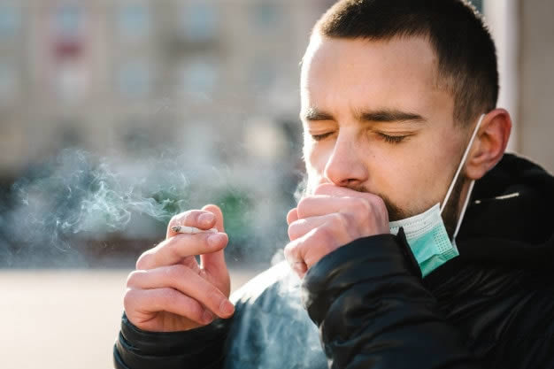 Homem fumando e tossindo com bronquite