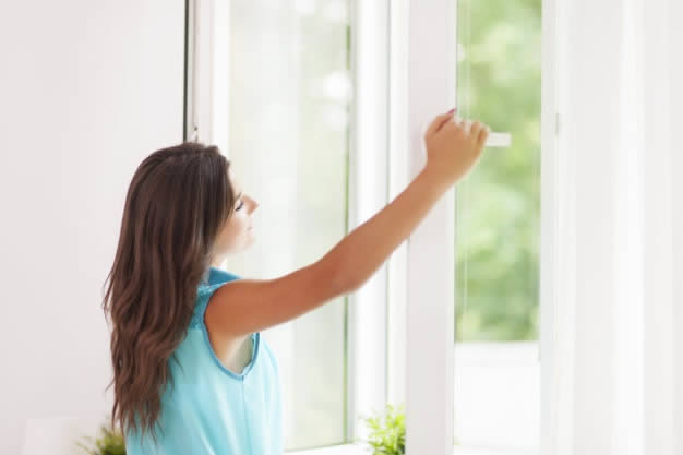 Mulher abrindo a janela para aumentar a ventilação do ambiente