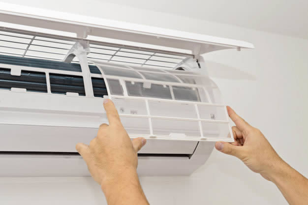 Homem removendo o filtro do ar condicionado